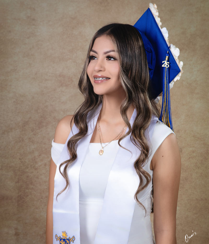 Graduation portrait of a girl in blue cap and white stole with class of 2026 tassel, studio backdrop