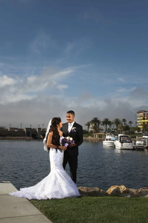 Bride and groom standing together by the marina with boats and palm trees, Oxnard wedding photography