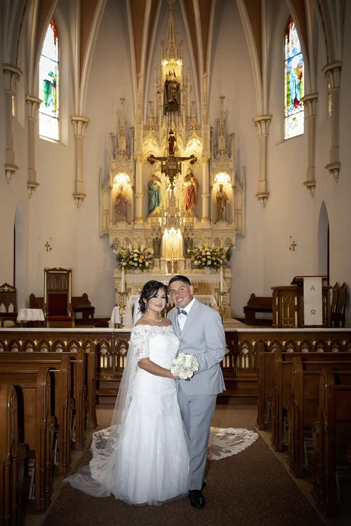 Bride and groom posing at the altar of a Gothic-style church, by wedding photographer Ventura County
