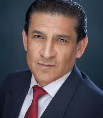 Professional corporate headshot of a man in a navy suit and red tie, studio portrait