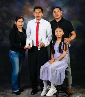 Religious celebration portrait of a teen son in a white shirt and red tie holding a ceremonial candle, with his mother holding a silver prayer book, his father, and his sister in a lavender dress seated on a stool.