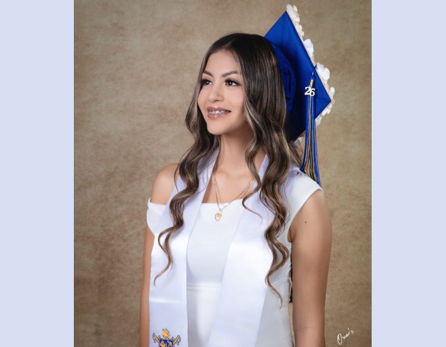 Graduation portrait of a girl in blue cap and white stole with class of 2026 tassel, studio backdrop