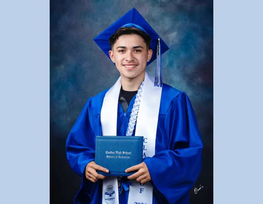 Smiling graduate in a royal blue cap and gown with a white Class of 2026 stole and braided lei, holding a Condor High School diploma.