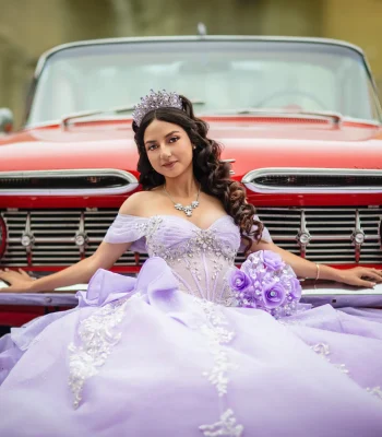 Quinceañera portrait in a lavender beaded gown with a crystal tiara, posing against a vintage red convertible