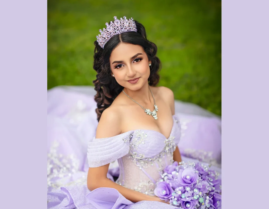 Quinceañera close-up portrait in a lavender off-the-shoulder gown with a beaded bodice and matching tiara, holding a lilac rose bouquet