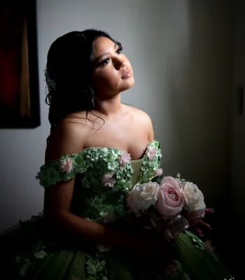Quinceañera close-up portrait in a red sequined gown with a matching red crystal tiara and necklace, holding a red rose bouquet against a red backdrop