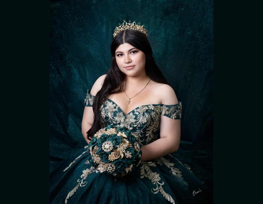 Quinceañera portrait in a pale blue beaded gown, standing in the aisle of a church with a glowing golden altar behind her