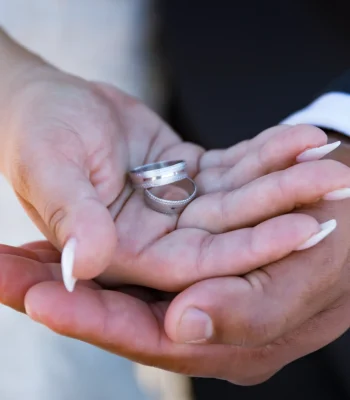Wedding rings close-up in couple's hands — two wedding bands held together in open palms