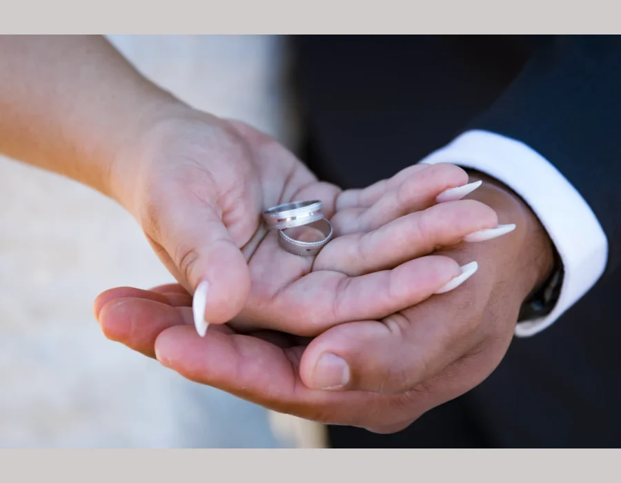 Wedding rings close-up in couple's hands — two wedding bands held together in open palms