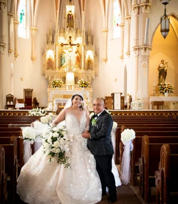 Wedding portrait of bride and father at church aisle — bride in ball gown walking down the aisle with her father