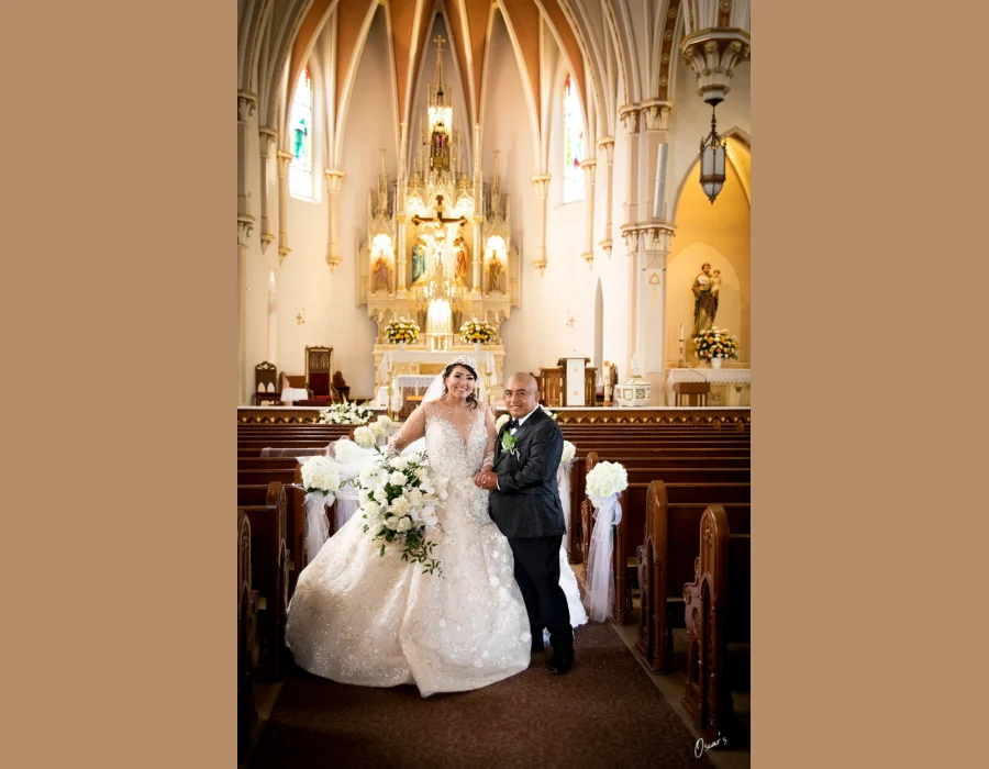 Wedding portrait of bride and father at church aisle — bride in ball gown walking down the aisle with her father