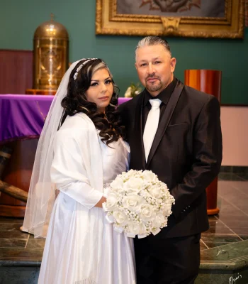 Wedding portrait of couple inside church sanctuary — formally dressed couple near the altar