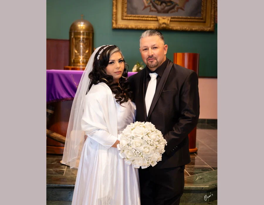 Wedding portrait of couple inside church sanctuary — formally dressed couple near the altar