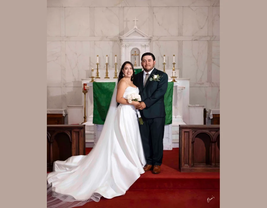 Wedding portrait at church altar — couple posing in front of a marble altar with green liturgical banners