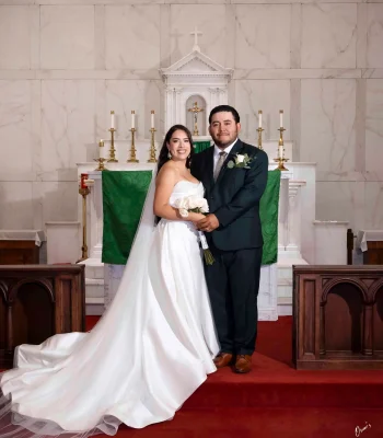 Wedding portrait at church altar — couple posing in front of a marble altar with green liturgical banners