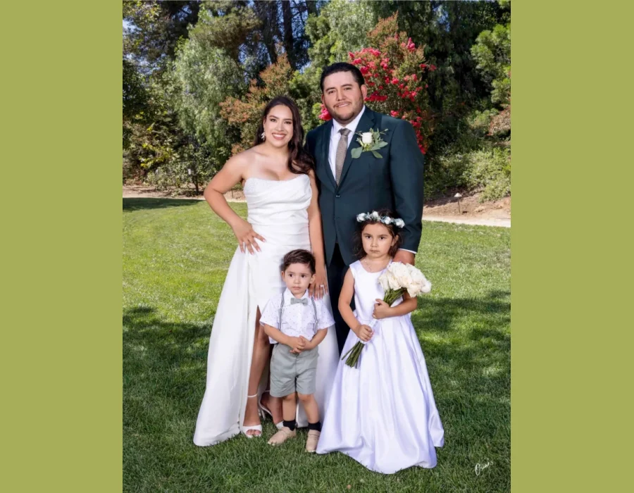 Wedding family portrait with children — bride and groom with a young boy and girl dressed in white, garden setting