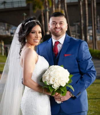 Wedding couple portrait with red tie — bride and groom smiling together outdoors near a marina