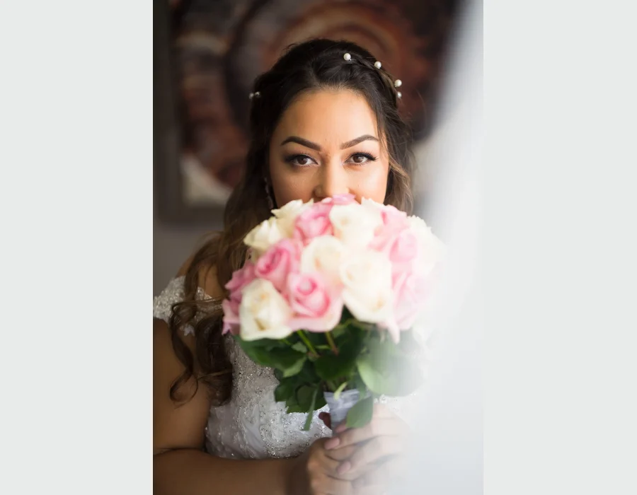 Bride holding bridal bouquet close-up — bride peeking over a bouquet of pink and white roses