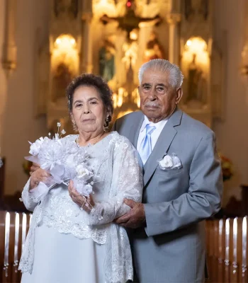 Wedding couple portrait inside church — older couple posing near the altar, bride holding a bouquet